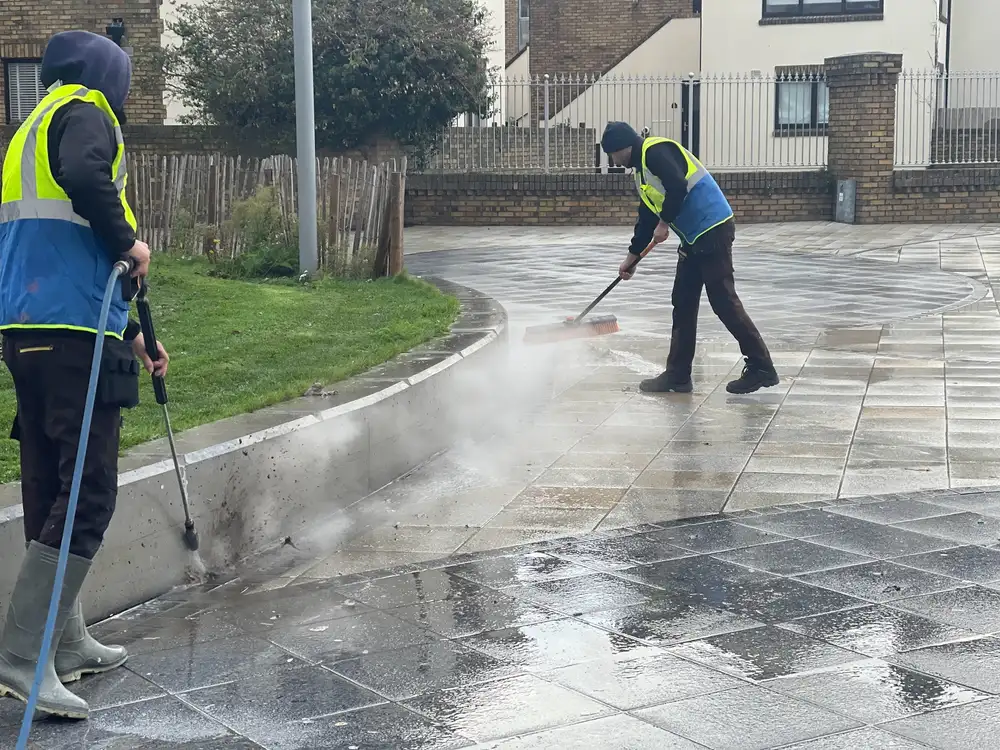 Two KAREDAN cleaners in hi-vis power washing paving outside a commercial development
